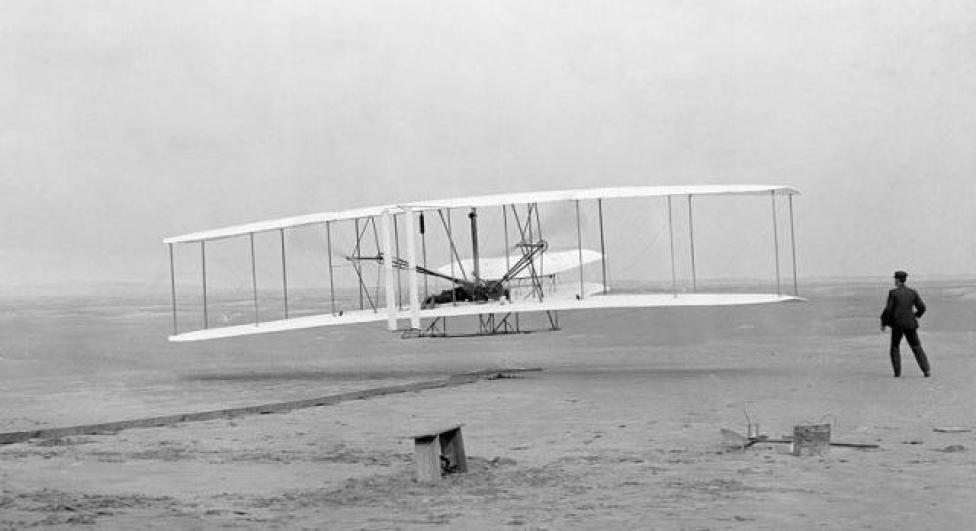 Samolot braci Wright – Flyer I – w czasie pierwszego w historii lotu (fot. John T. Daniels/Domena publiczna/Wikimedia Commons)