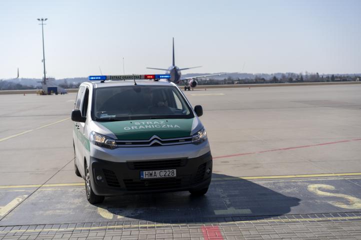Samochód Straży Granicznej na płycie lotniska w Gdańsku - samolot w tle (fot. A. Kubiak)