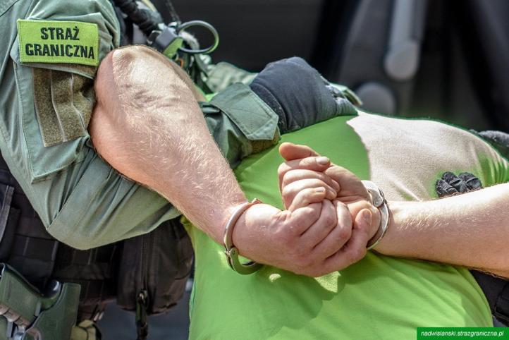 Funkcjonariusz Straży Granicznej prowadzi zatrzymanego w kajdankach (fot. Nadwiślański OSG)