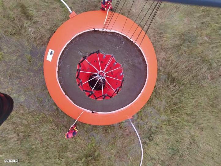 Śmigłowiec S-70i Black Hawk z podwieszanym strażackim zbiornikiem Bambi Bucket nabiera wodę (fot. policja.pl)