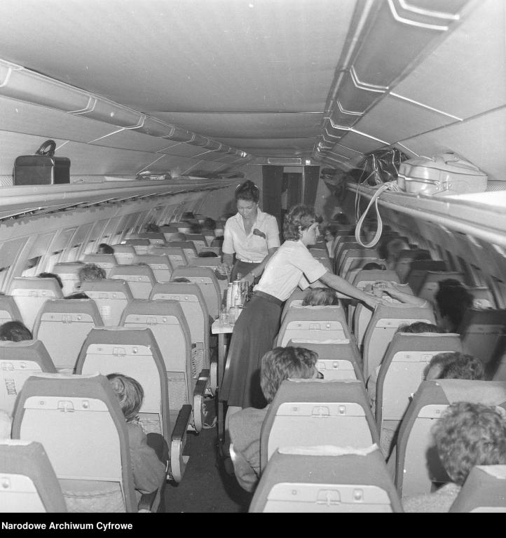 Pokład samolotu Iljuszyn Ił-62M. Stewardesa z dzbankiem obsługuje pasażerów, 1972-1980 (fot. Narodowe Archiwum Cyfrowe)