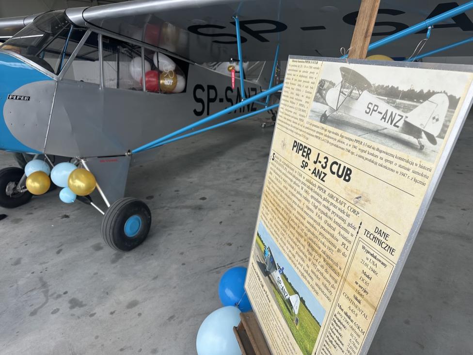Piper J-3 Cub i tablica informacyjna w hangarze (fot. Aeroklub Ziemi Piotrkowskiej)