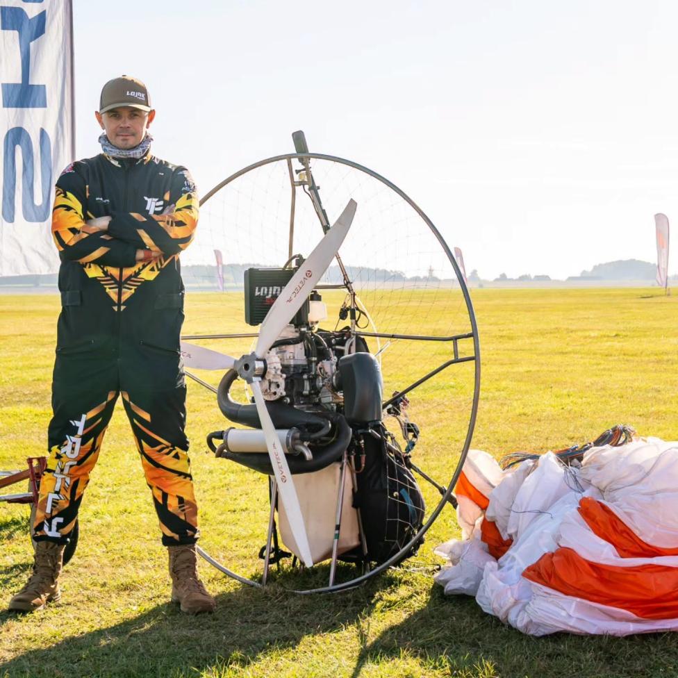Paweł 'Lojak' Kozarzewski obok paralotni i napędu na lotnisku (fot. Aeroklub Polski)