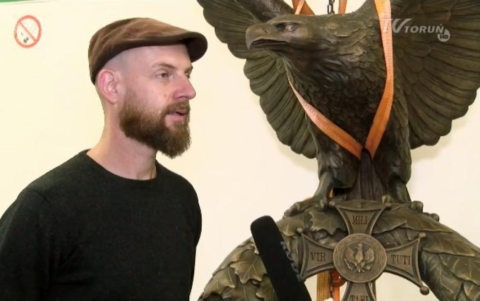 Maciej Jagodziński-Jagenmeer obok zrekonstuowanego orła (fot. kadr z filmu TV Toruń)