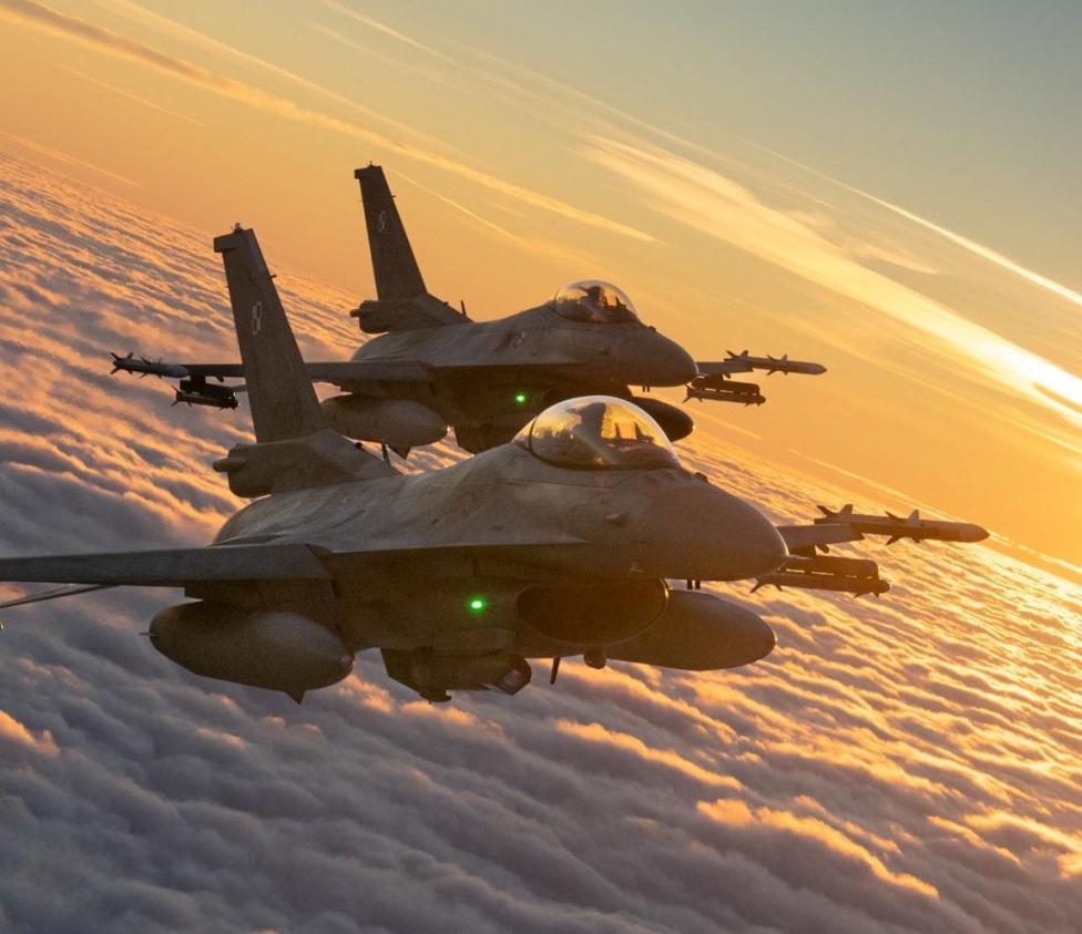 Dwa samoloty F-16 Polskich Sił Powietrznych w locie nad chmurami o zachodzie słońca - widok z ukosa (fot. Sztab Generalny WP/Facebook)