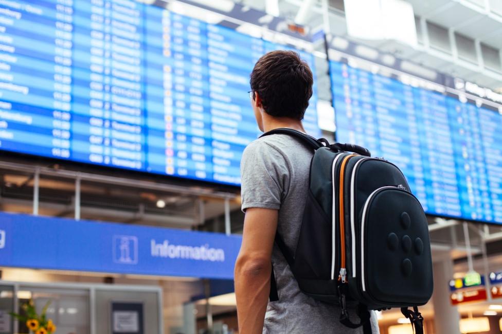 Pasażer przed tablicą odlotów na lotnisku (fot. Shutterstock)