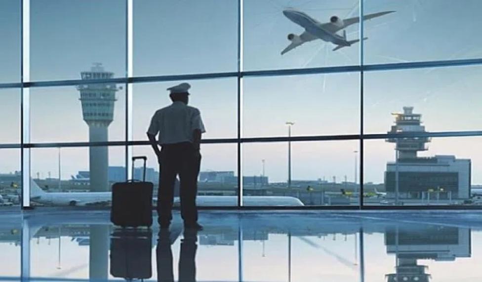 Pilot z walizką w terminalu patrzy na lotnisko (fot. AVweb)