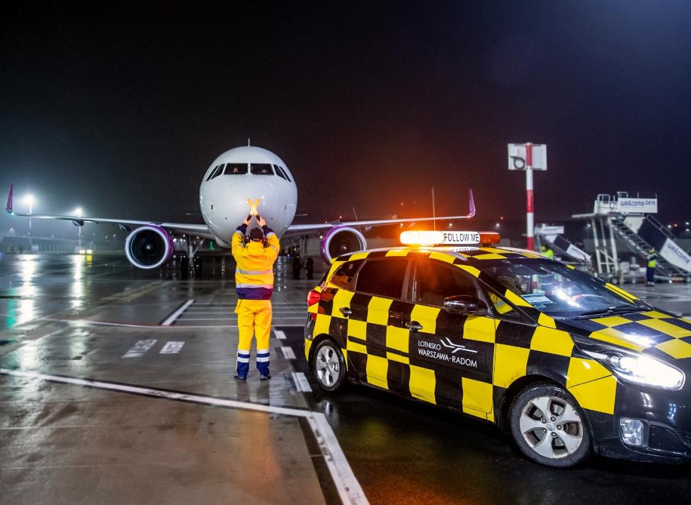Port Lotniczy Warszawa-Radom - Marshaller zatrzymuje A321 na miejscu postojowym nocą (fot. Lotnisko Warszawa-Radom, Facebook)