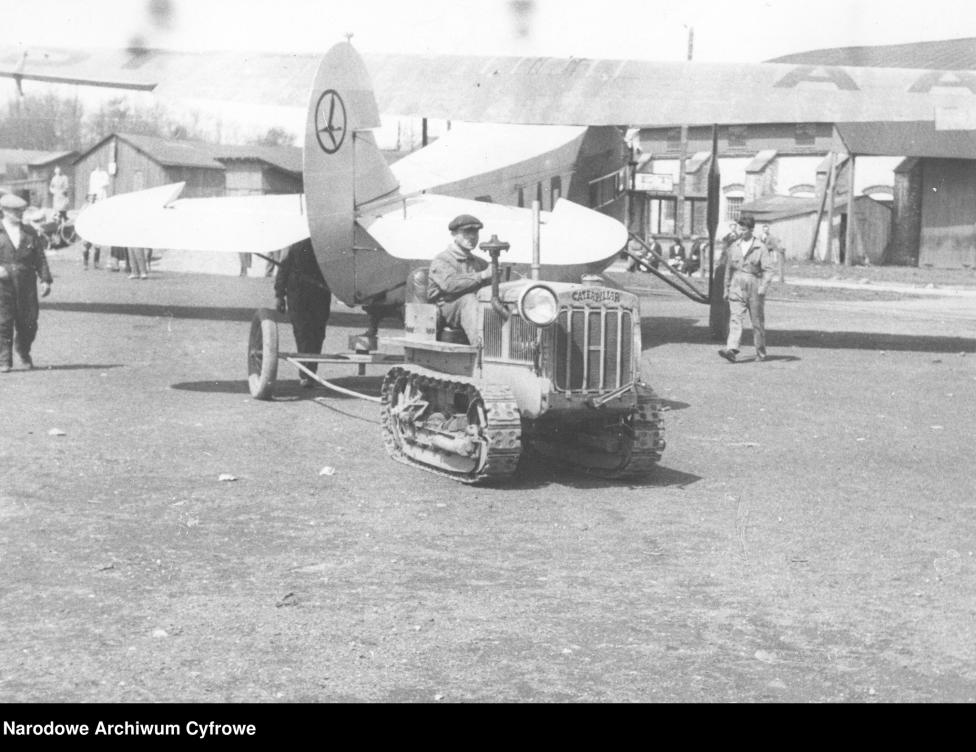 Lotnisko Mokotowskie w Warszawie. Ciągnik gąsienicowy marki Caterpillar wprowadzający do hangaru samolot pasażerski typu Fokker F-VII/1m. Na ogonie samolotu widoczne logo LOT-u, 1931-1933 (fot. Narodowe Archiwum Cyfrowe)