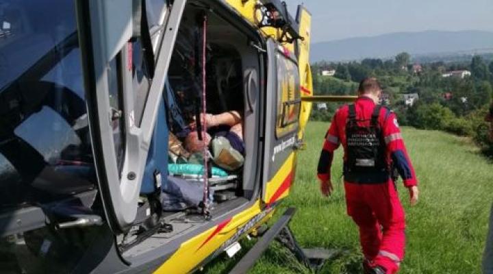 Ratownik z Grupy Beskidzkiej GOPR przekazuje poszkodowanego paralotniarza do śmigłowca LPR (fot. GOPR Beskidy/Facebook)