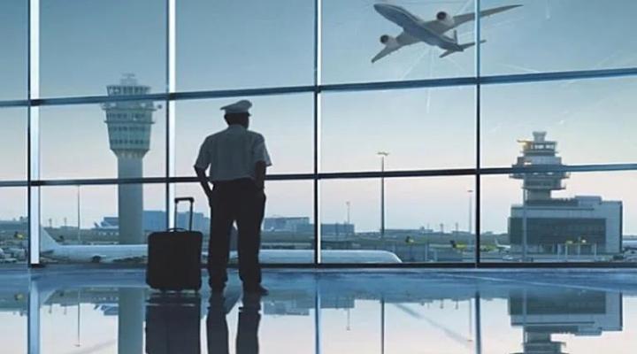 Pilot z walizką w terminalu patrzy na lotnisko (fot. AVweb)