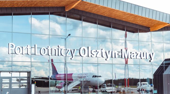 Port Lotniczy Olsztyn-Mazury - napis na termnalu i odbicie samolotu w szybie (fot. Port Lotniczy Olsztyn-Mazury)