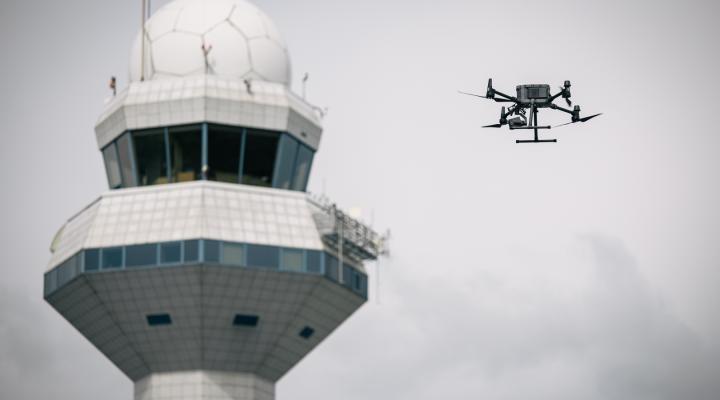 Dron w locie - wieża kontroli lotów na Lotnisku Chopina w tle (fot. PAŻP)