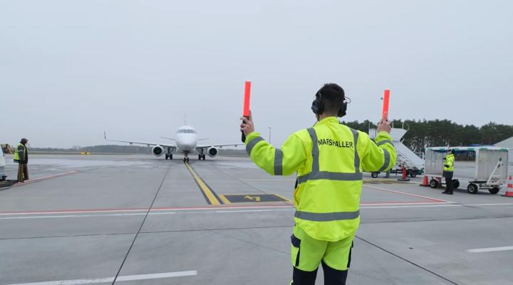 Marszałek lotniczy wskazuje pilotom drogę do zaparkowania samolotu na lotnisku w Bydgoszczy (fot. Port Lotniczy Bydgoszcz)