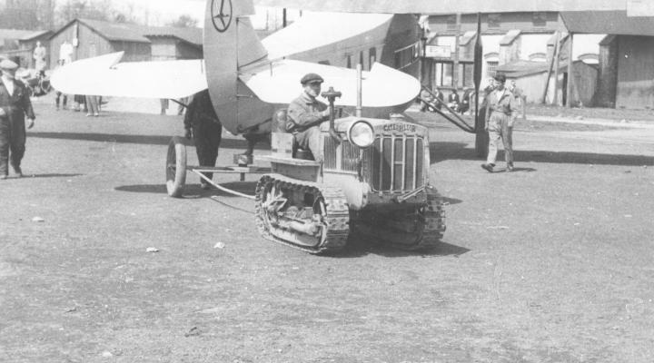 Lotnisko Mokotowskie w Warszawie. Ciągnik gąsienicowy marki Caterpillar wprowadzający do hangaru samolot pasażerski typu Fokker F-VII/1m. Na ogonie samolotu widoczne logo LOT-u, 1931-1933 (fot. Narodowe Archiwum Cyfrowe)